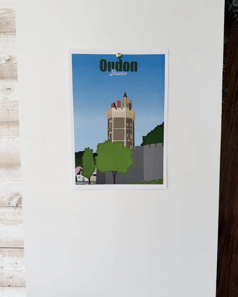 Affiche représentant le Tour d'Oudon accrochée au mur à l'aide d'un trombone scotché au mur, et maintenue avec un aimant.