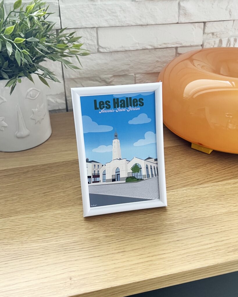 Affiche représentant les Halles de Ancenis-Saint-Géréon, dans un cadre sur pied posé sur une commode.